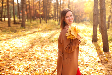 Happy young woman in a beige coast walks outdoors in autumn park, concept autumn. High quality photo