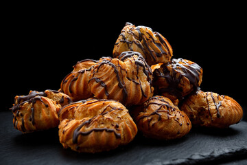 Profitrolls with chocolate on a dark background