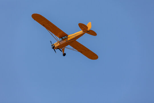 Yellow plane. A single engine plane crosses the blue sky. Transportation.