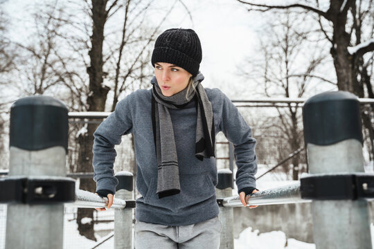 Athletic woman during her winter outdoor workout on parallel bars