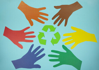 The international recycling sign is a Mobius loop and multicolored hands cut out of paper on a blue background. November 15 - Waste Recycling Day