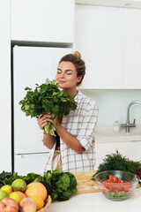 Woman with big bunch of green coriander during cooking in the kitchen