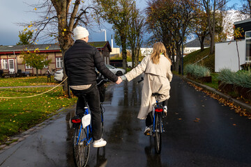 Copenhagen, Denmark A young couple ride bikes after the rain and hold hands.