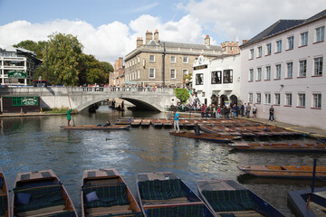 Boats, and punts sitting idle on a river running through Cambridge University, UK.