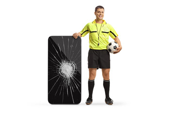 Full length portrait of a football referee standing next to a smartphone with broken screen