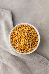 A bowl of yellow dry peas on a light background
