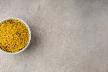 White bowl with yellow vermicelli on a light background