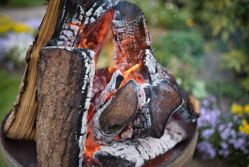 Stacks of logs are burning in a fire barrel at a medieval market
