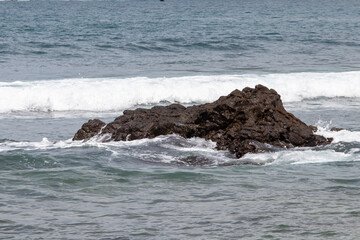 View of Wediombo Beach, Yogyakarta, Indonesia with a row of corals breaking the waves