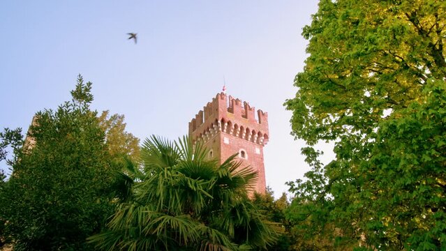Top of Lazise Castle seen behind green trees on sunny day