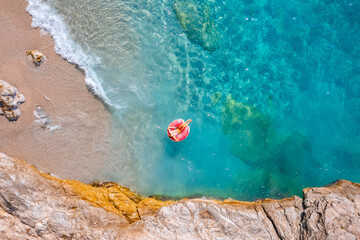 Aerial top view young woman swimming with donut pink inflatable swim ring in blue sea. Concept tropical paradise travel relax