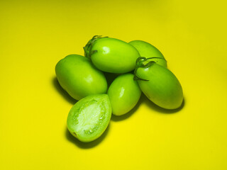 Green tomatoes on a yellow background. The concept of an unripe vegetable.   green vegetables. Salting product.