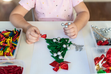 Children's hands creating Christmas tree from dyed pasta for the holiday of Christmas. Sensory play...