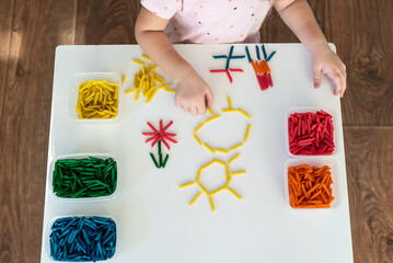 Child hands playing with dyed pasta for sensory play and craft activities. Learning colors activity for kids, activities Montessori, games for fine motor skills, play for toddler