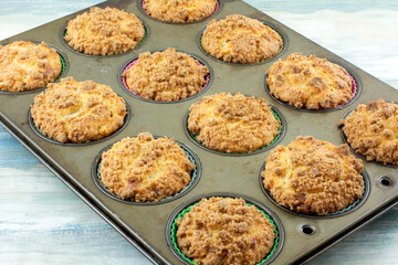Dozen Baked breakfast cinnamon muffins with crumble topping in muffin pan - Powered by Adobe