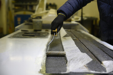 Installation of fiberglass: worker manually makes a component in glass fiber for automotive use....