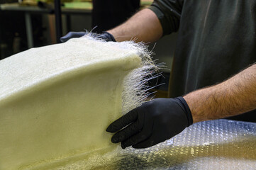 Installation of fiberglass: worker manually realizes a component in glass fiber for automotive use....