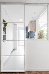 Kitchen with plain white cabinets, integrated appliances in the same color and sliding glass door with metal frames