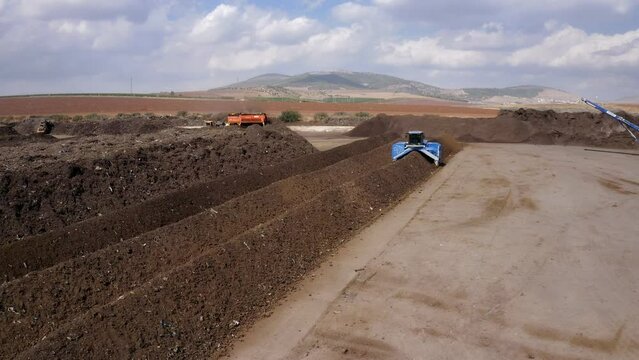 Aerial view of an industrial compost production site. Large compost turning machine mixing compost piles