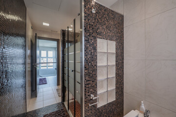 Large tiled shower room with dark tiles, matching floors and wooden strips, light tiles and a large window in the background