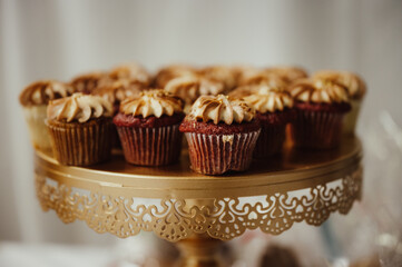 a single red velvet cupcake with golden brown icing stands out from the group of cupcakes on a golden platter