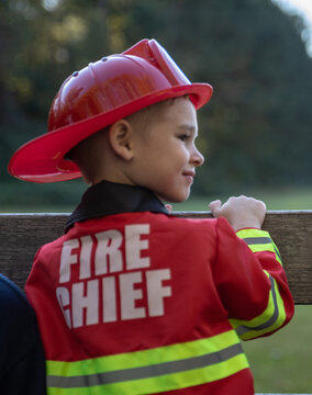 Young blonde-haired child dressed up in fire fighter chief uniform for Halloween