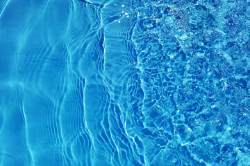 Defocus blurred transparent blue colored clear calm water surface texture with splashes and bubbles. Trendy abstract nature background. Water waves in sunlight with copy space. Blue watercolor shining