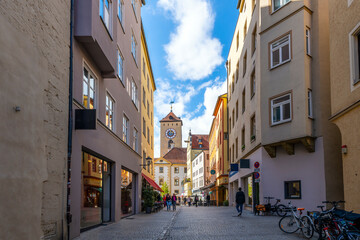 View of the Brückturm Clock Tower from a picturesque street of shops in the Altstadt or Old Town area of the medieval, Bavarian town of Regensburg, Germany.