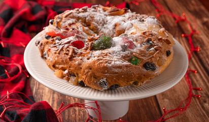 Portuguese Bolo Rei is a traditional Chrismas cake with fruits and icing on wooden table
