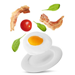 Tasty fried chicken egg, bacon, tomato and basil leaves falling into plate on white background
