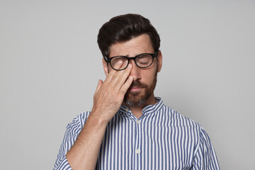 Man suffering from eyestrain on light grey background