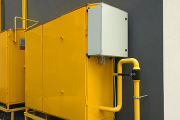 Yellow gas distribution cabinet near brown wall outdoors