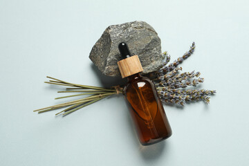 Flat lay composition with bottle of face serum, stone and beautiful flowers on light grey background