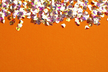 Pile of shiny glitter on orange background, flat lay. Space for text