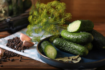 Fresh cucumbers and other ingredients prepared for canning on wooden table, closeup