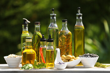 Different cooking oils and ingredients on wooden table against blurred green background