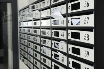 New mailboxes with keyholes, numbers and receipts near entrance in post office