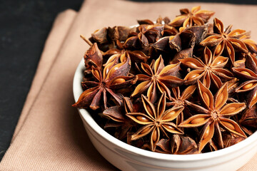 Bowl with aromatic anise stars on table, closeup