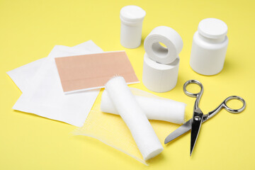 White bandage rolls and medical supplies on yellow background