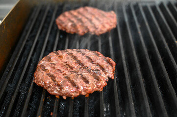 Grilling burgers on barbecue with hot coal. Delicious minced meat on barbecue. BBQ. Preparing hamburger. 