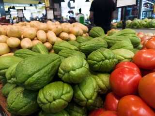 Fresh chayote, potato and tomato at the supermarket. Vegetables and fruits exposed for the consumer to choose