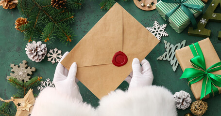 Hands of Santa Claus with letter on green background, top view