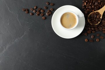 Cup of aromatic coffee and beans on black table, flat lay. Space for text