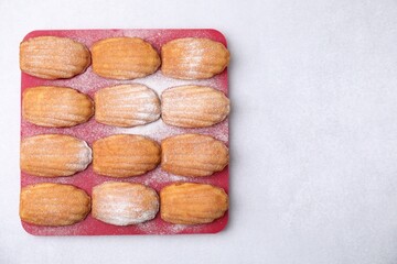 Delicious madeleine cookies in baking mold on white table, top view. Space for text