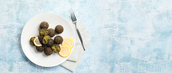 Plate with tasty falafel balls on light blue background with space for text, top view