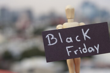 Wooden doll holding a sign with the words black friday outdoors
