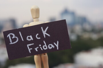 Wooden doll holding a sign with the words black friday outdoors