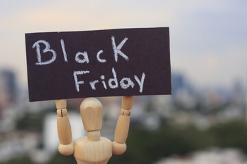 Wooden doll holding a sign with the words black friday outdoors