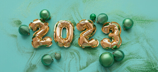 Figure 2023 made of balloons and Christmas balls on green background