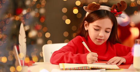 Cute girl writing letter to Santa at home on Christmas eve